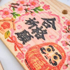 桜とだるまをデザインした木製絵馬の印刷拡大